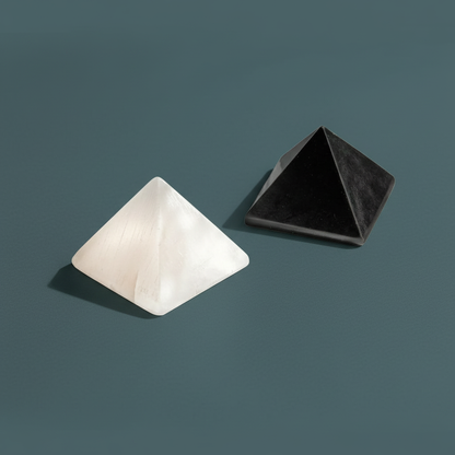 A pair of white and black crystal pyramids displayed on a muted teal textured surface under soft diffused light. — for Carpe Diem Dream