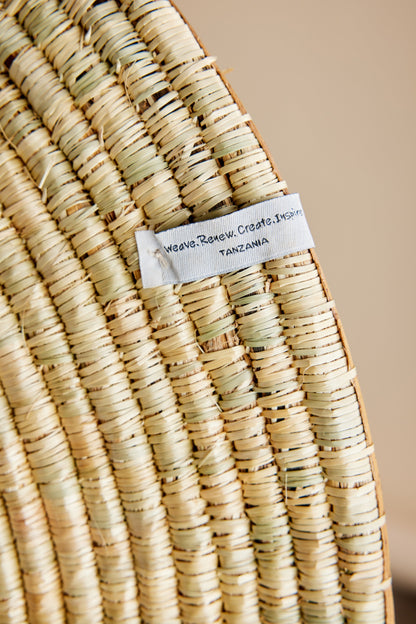 Close-up of Sunrise Wall Basket handwoven natural grass texture with visible artisan tag and woven construction detail. — for Carpe Diem Dream