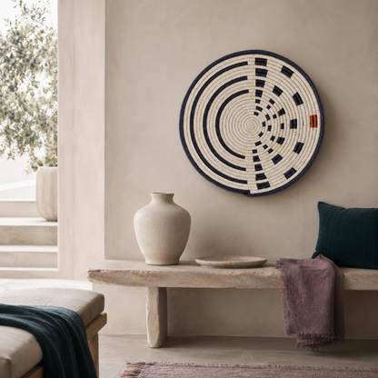 Large Sunrise Wall Basket styled on a calm sanctuary wall with travertine bench, dark teal pillow, mauve textile, soft stone ceramics, and cool neutral interior accents. — for Carpe Diem Dream