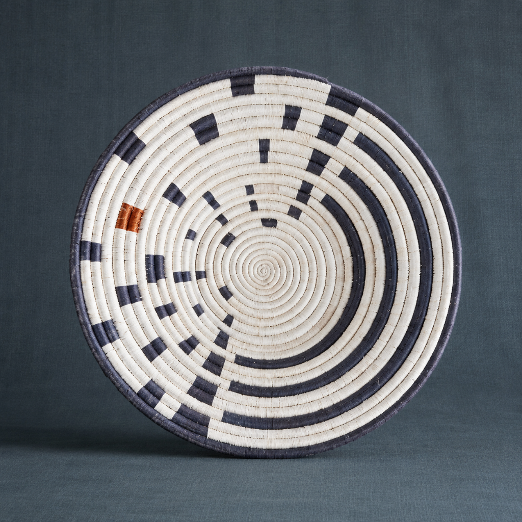 Large Sunrise Wall Basket handwoven decorative wall basket with navy and natural concentric pattern on a dark teal textured backdrop. — for Carpe Diem Dream