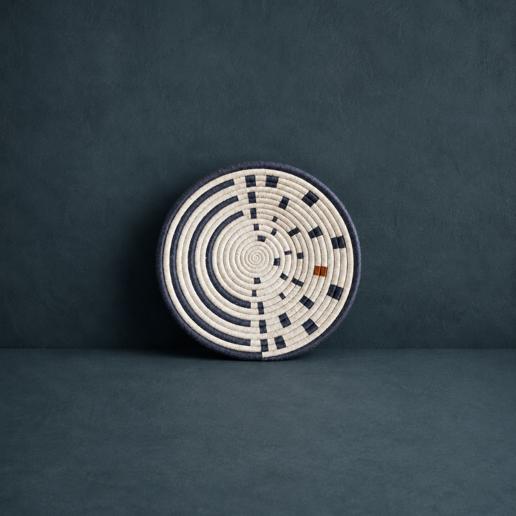 Small Sunrise Wall Basket handwoven wall basket with navy and natural spiral pattern on a dark teal textured backdrop — Carpe Diem Dream
