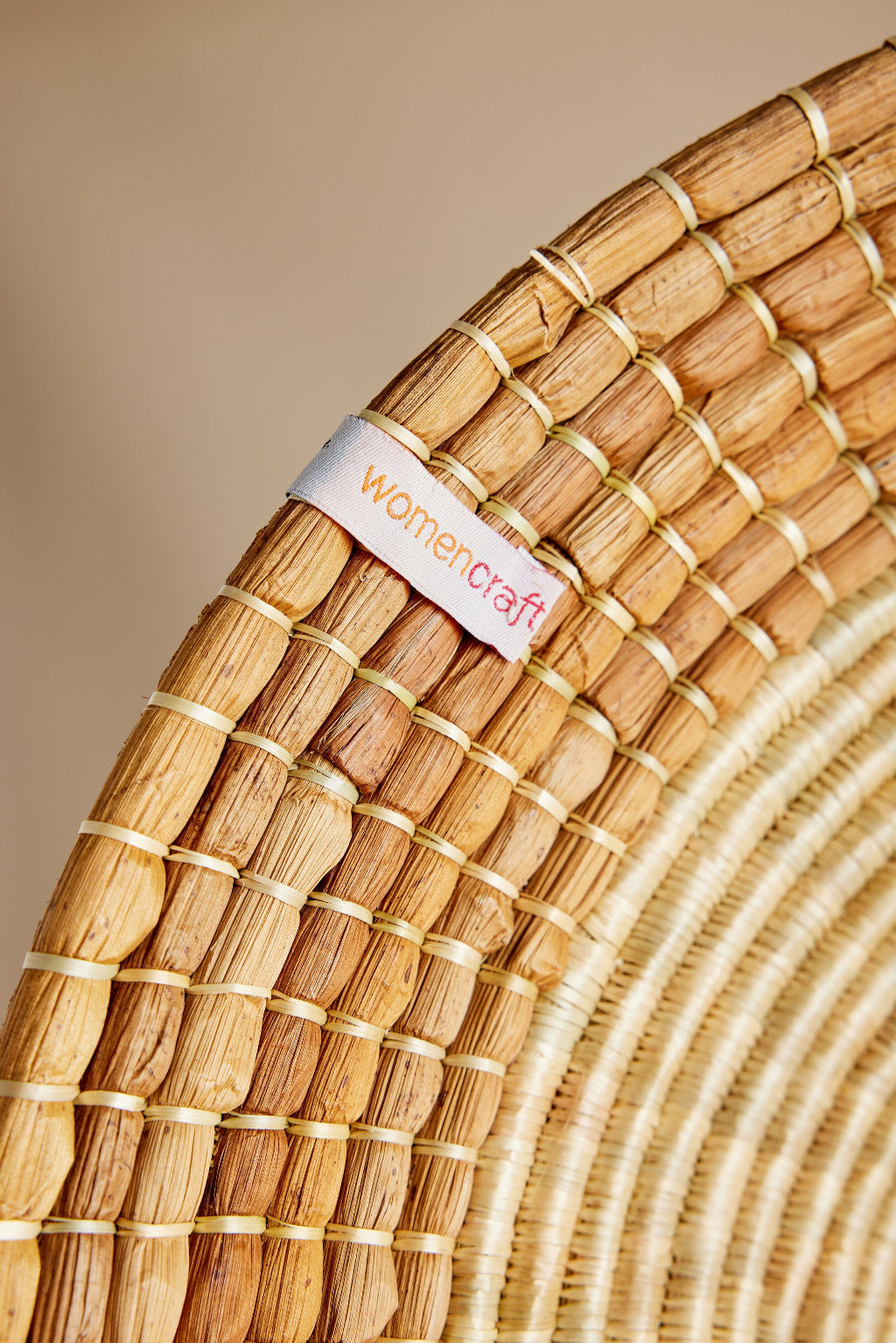 Close-up of Sunrise Wall Basket handwoven natural grass texture with WomenCraft tag and artisan stitching detail. — for Carpe Diem Dream
