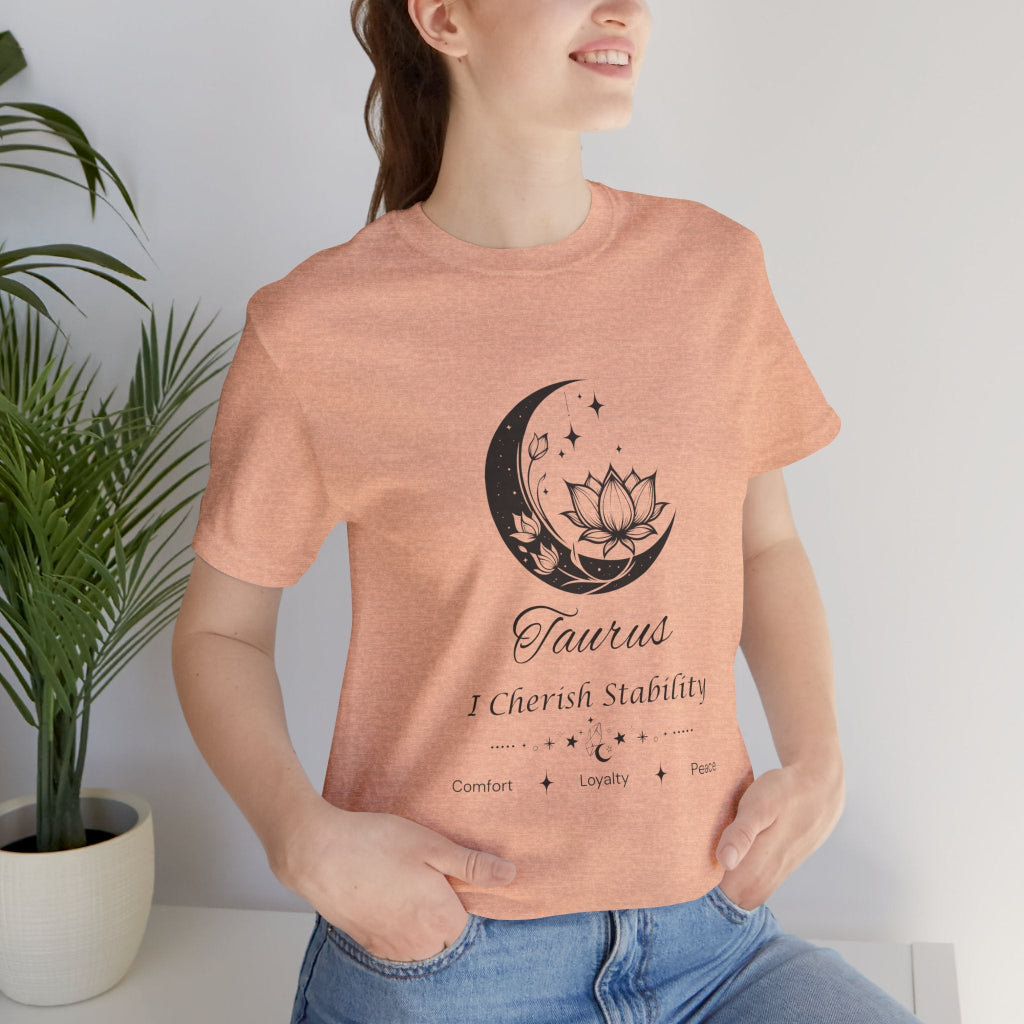 Model wearing a Heather Peach Taurus Moon I Cherish Stability zodiac T-shirt with black moon-inspired lotus, floral, and celestial artwork. — for Carpe Diem Dream