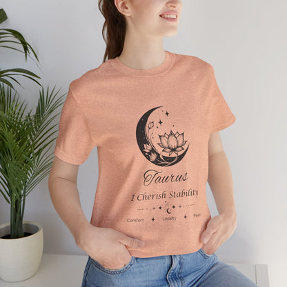 Model wearing a Heather Peach Taurus Moon I Cherish Stability zodiac T-shirt with black moon-inspired lotus, floral, and celestial artwork. — for Carpe Diem Dream