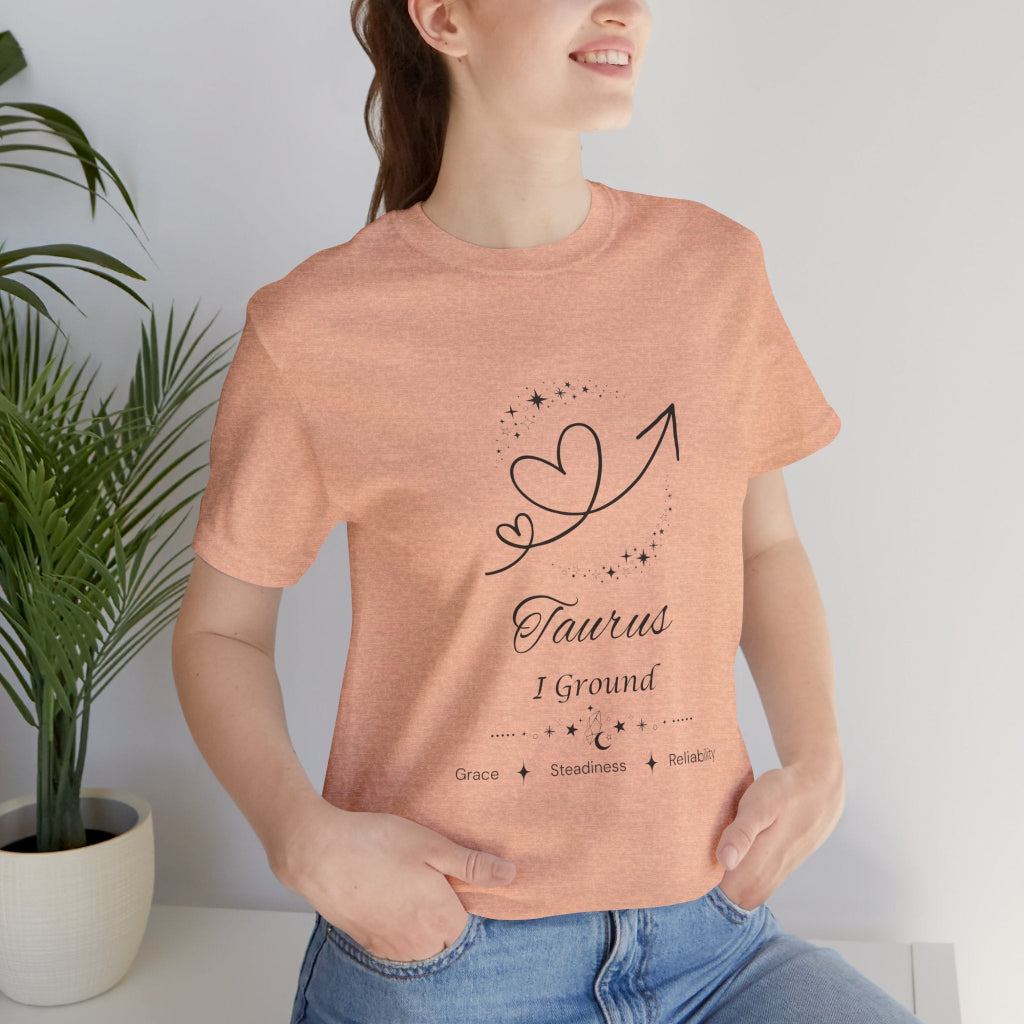 Model wearing a Heather Peach Taurus Rising I Ground zodiac T-shirt with black celestial heart and arrow artwork. — for Carpe Diem Dream