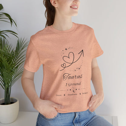 Model wearing a Heather Peach Taurus Rising I Ground zodiac T-shirt with black celestial heart and arrow artwork. — for Carpe Diem Dream