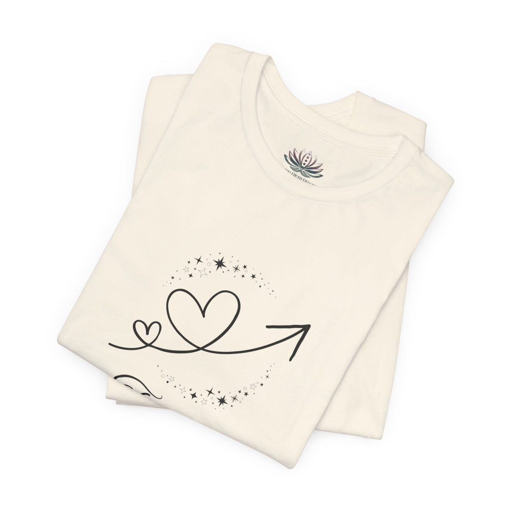 Taurus Rising I Ground zodiac T-shirt in Natural with black celestial heart and arrow artwork, shown folded in a supplier mockup. — for Carpe Diem Dream