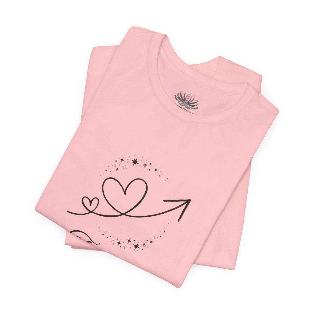 Taurus Rising I Ground zodiac T-shirt in pink with black celestial heart and arrow artwork, shown folded in a supplier mockup. — for Carpe Diem Dream