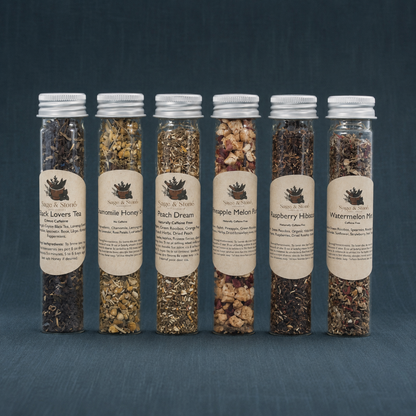 Fruity Tea Sampler with six labeled tea tubes on a dark teal linen backdrop. — for Carpe Diem Dream