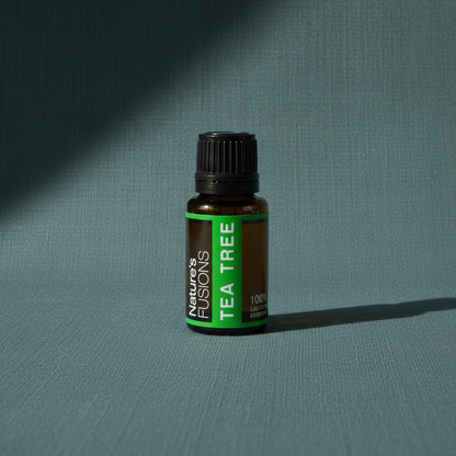 Amber glass bottle of Tea Tree Essential Oil standing upright on muted teal textured background with soft directional shadow. — for Carpe Diem Dream