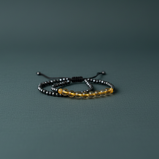 Mindfulness bracelet with glossy black hematite and warm citrine beads arranged on a muted teal matte surface with soft diffused lighting — for Carpe Diem Dream