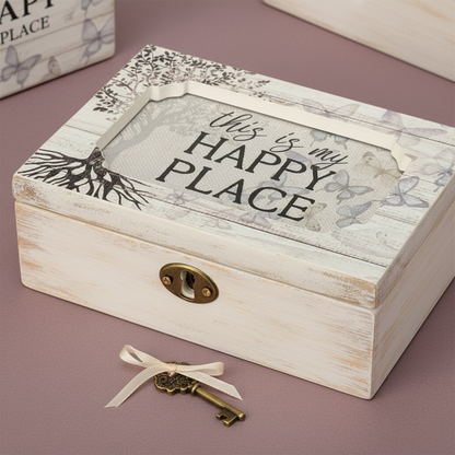 Close-up of a wooden “This Is My Happy Place” music box with vintage key resting on a soft muted mauve surface — for Carpe Diem Dream.