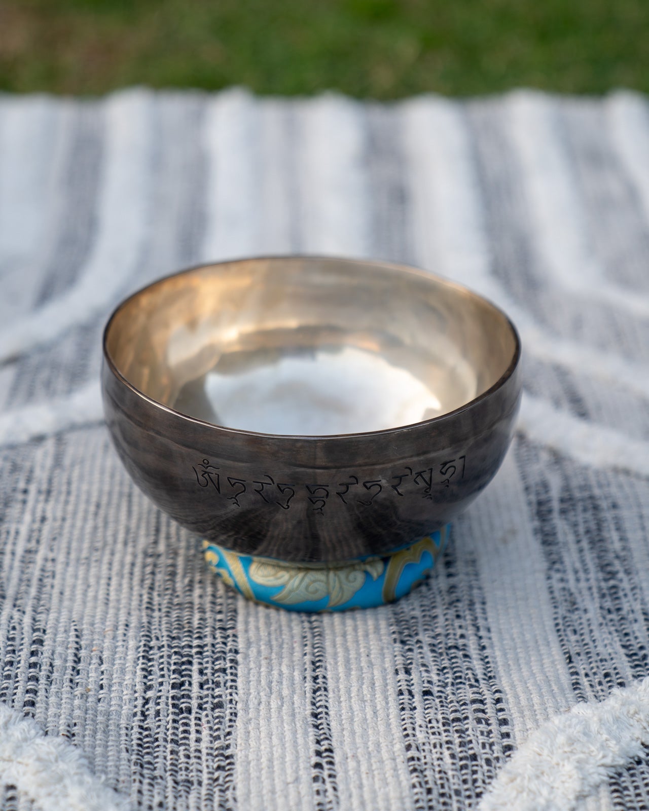 Back view of a Throat Chakra New Moon singing bowl tuned to G note showing engraved mantra symbols on the bronze metal surface. — for Carpe Diem Dream
