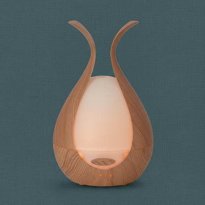 A walnut finish ultrasonic diffuser displayed upright on a dark teal linen surface with soft natural light. — for Carpe Diem Dream