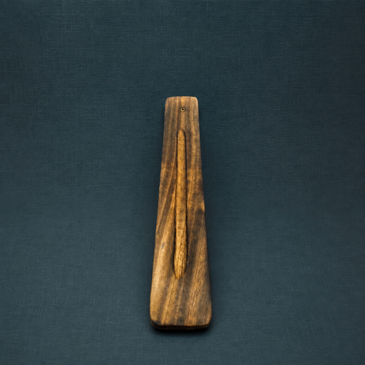 Traditional wood incense holder with natural brown grain and a recessed ash-catching center displayed on a textured dark teal studio background. — for Carpe Diem Dream
