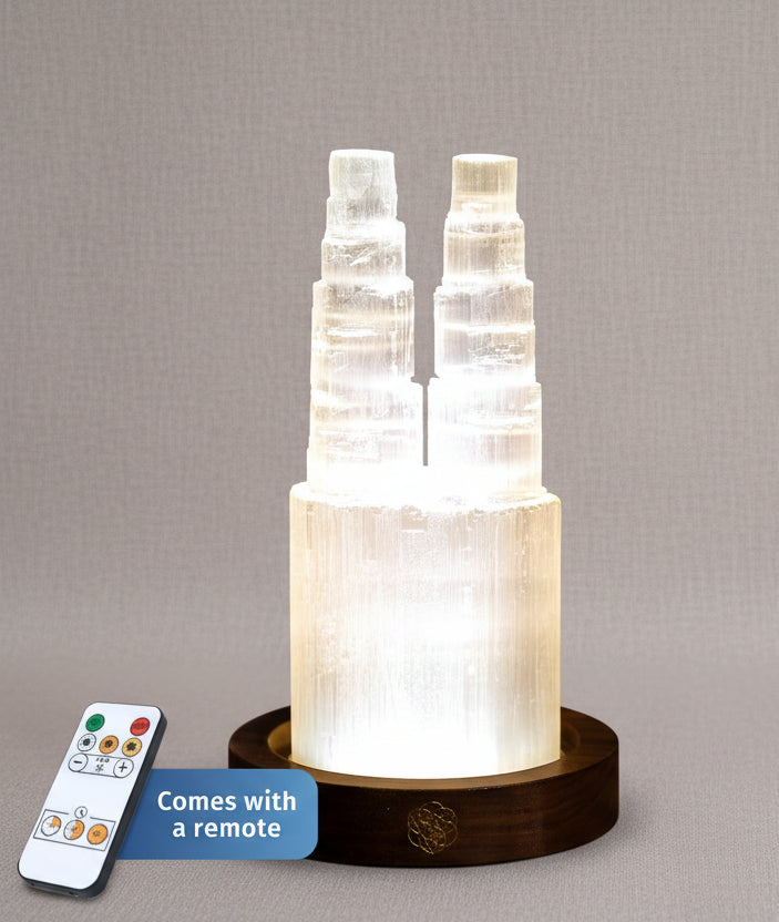 Two tower selenite crystal lamp glowing on a wooden base with a handheld remote control shown beside it. — for Carpe Diem Dream