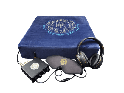 A vibroacoustic therapy zafu meditation cushion bundle showing a navy cushion with a gold lotus mandala, a compact black amplifier, over-ear headphones, a satin eye mask, and connecting cables on a transparent background. — for Carpe Diem Dream
