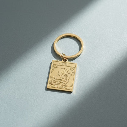 The Moon keyring from the Vintage Tarot Card Keyring collection, featuring an engraved gold moon and stars design on a soft cool-toned background, styled for Carpe Diem Dream.