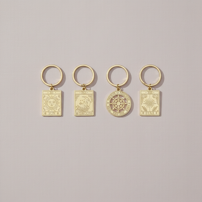 Set of four vintage-style gold tarot keyrings displayed on a soft neutral background, each engraved with symbolic sun, moon, wheel, and star designs – for Carpe Diem Dream.