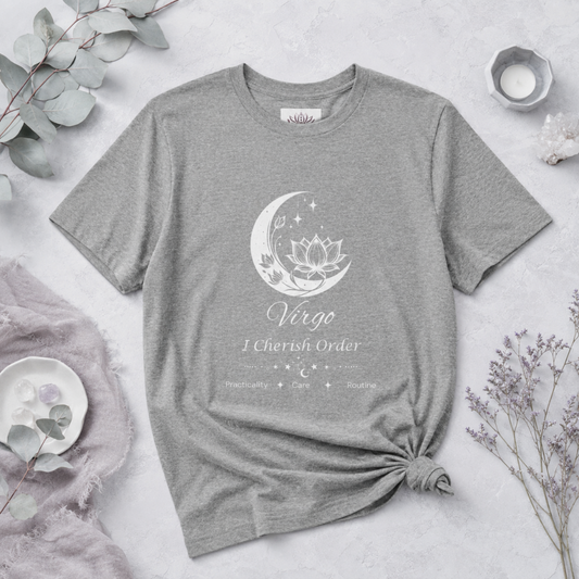 Virgo Moon I Cherish Order zodiac T-shirt in Athletic Heather with white moon-inspired lotus, floral, and celestial artwork and Practicality, Care, Routine text, styled in a cool-toned studio botanical flat lay with eucalyptus, lavender, crystals, and ceramic accents. — for Carpe Diem Dream