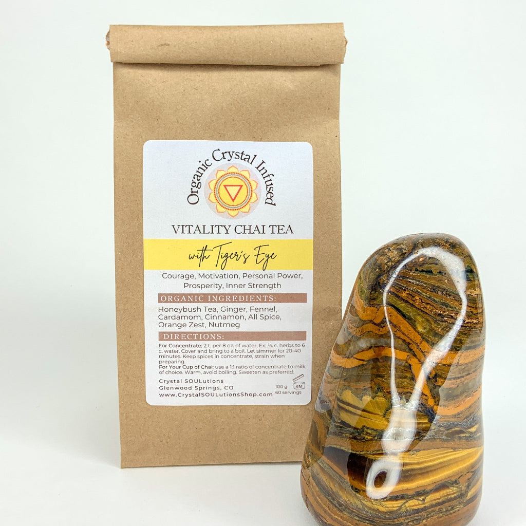 Vitality Chai Tea – Organic Crystal-Infused Tea with Tiger's Eye, 100 g kraft bag featuring the authentic product packaging alongside a polished Tiger's Eye crystal on a clean white background — for Carpe Diem Dream