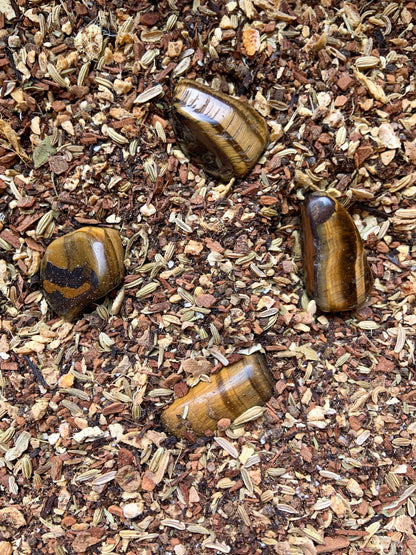 Organic chai ingredients for Vitality Chai Tea arranged with polished Tiger's Eye crystals, showing the loose herbal blend used in the crystal-infused tea — forCarpe Diem Dream
