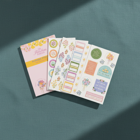 Wellness Edit planner sticker book with interior sticker sheets displayed in an angled stack on a teal textured background — for Carpe Diem Dream
