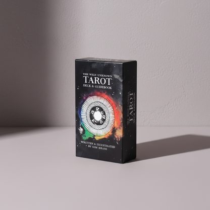 The Wild Unknown Tarot Deck box by Kim Krans displayed upright against a neutral textured wall with soft directional studio lighting and a clean, minimal composition. — for Carpe Diem Dream