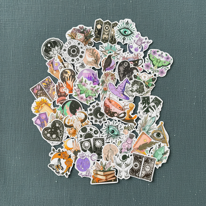 Close-up view of the Witchy Boho matte sticker set featuring assorted celestial, tarot, floral, and mystical designs on a textured teal background. — for Carpe Diem Dream
