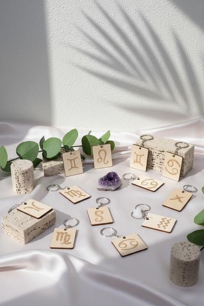 Wood Engraved Zodiac Keychain featuring astrology symbol, handcrafted from natural wood on botanical pink silk cork with amethyst background for Carpe Diem Dream.