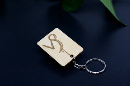 Wood Engraved Zodiac Keychain featuring Capricorn astrology symbol, handcrafted from natural wood blue background with green plant for Carpe Diem Dream