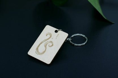 Wood Engraved Zodiac Keychain featuring Leo astrology symbol, handcrafted from natural wood blue background with green plant for Carpe Diem Dream