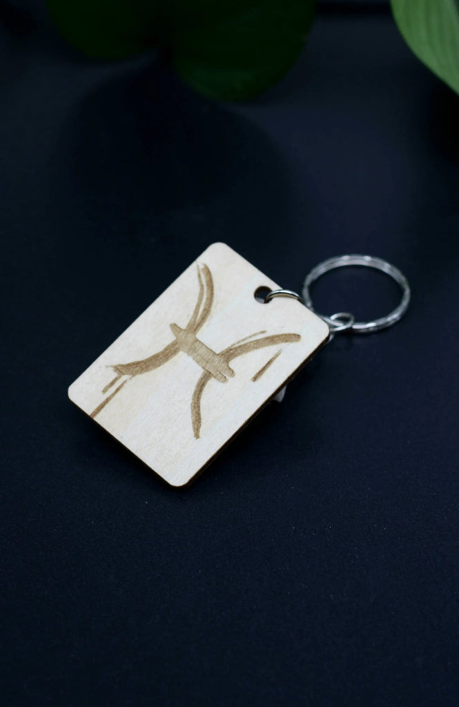 Wood Engraved Zodiac Keychain featuring Pisces astrology symbol, handcrafted from natural wood blue background with green plant for Carpe Diem Dream