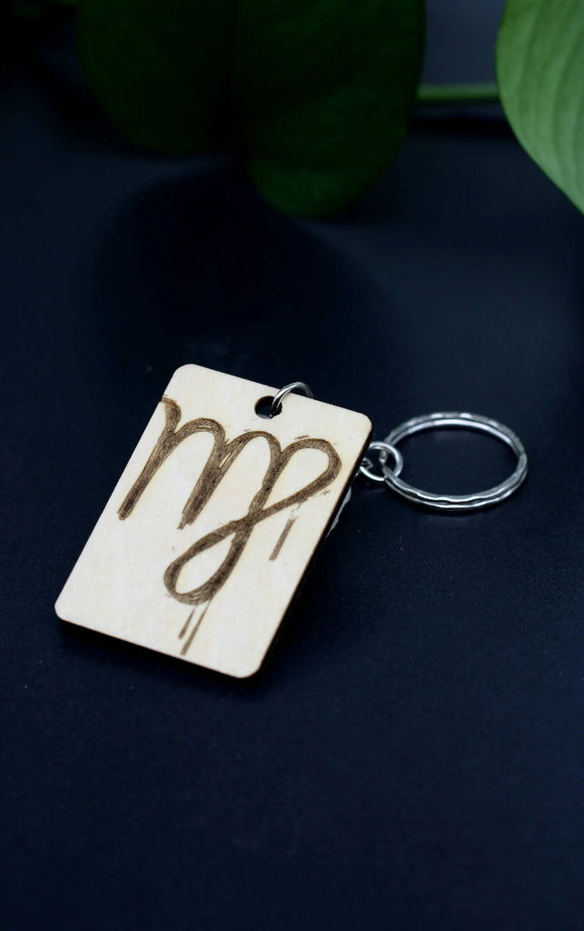 Wood Engraved Zodiac Keychain featuring Virgo astrology symbol, handcrafted from natural wood blue background with green plant for Carpe Diem Dream