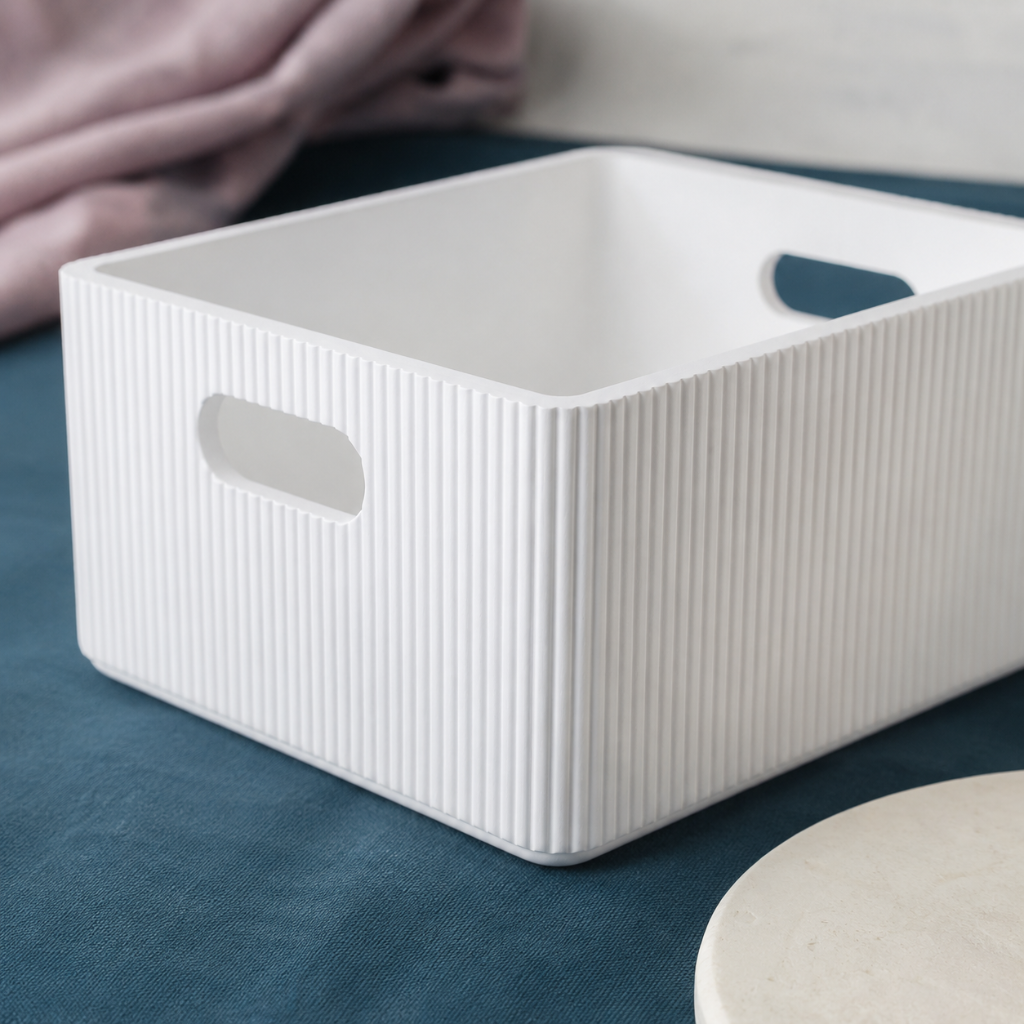 Close-up of a white wooden ribbed storage bin showing fluted texture, rounded corners, and smooth cutout handles with soft mauve linen accents. — for Carpe Diem Dream