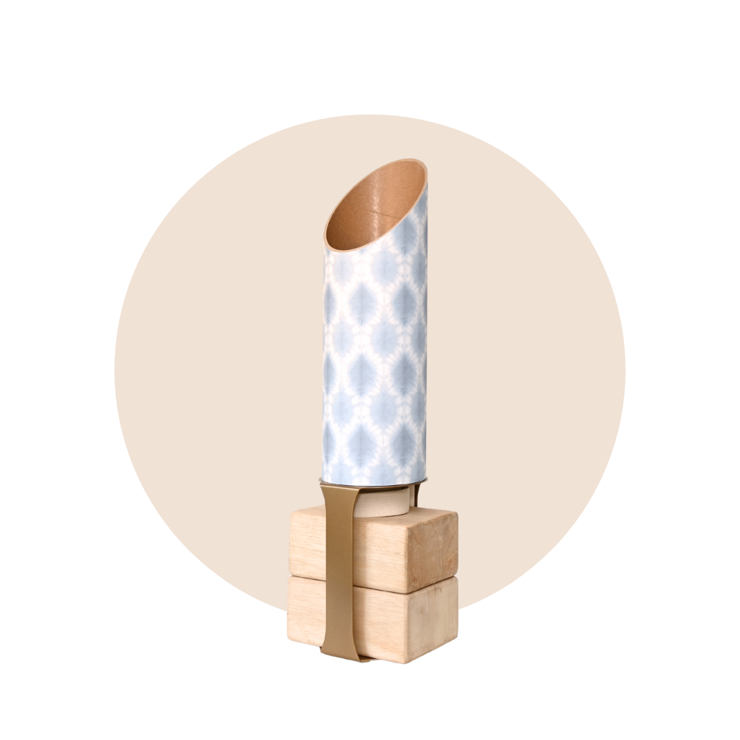 Light blue and white patterned yoga storage tube with a gold stand and wooden yoga blocks displayed on a beige circular background. — for Carpe Diem Dream