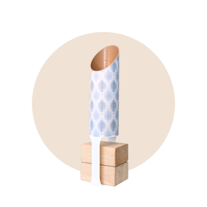 Light blue and white patterned yoga storage tube with a white stand and wooden yoga blocks displayed on a beige circular background. — for Carpe Diem Dream
