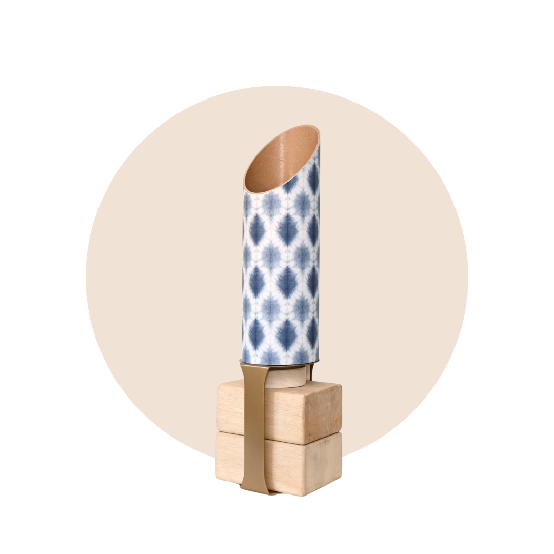 Navy and white patterned yoga storage tube with a gold stand and wooden yoga blocks displayed on a beige circular background. — for Carpe Diem Dream