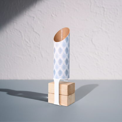 Light blue and white patterned yoga storage tube with a white block stand and two wooden yoga blocks on a cool gray surface against a textured white wall. — for Carpe Diem Dream