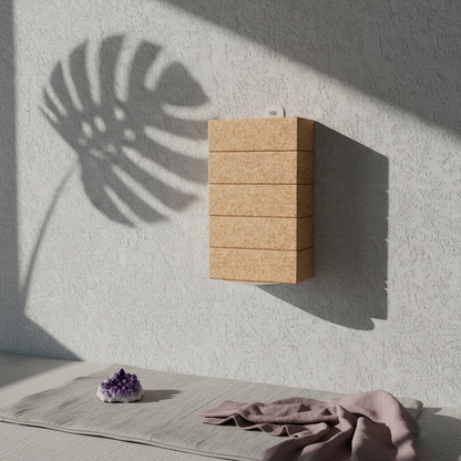White wall-mounted yoga block bracket holding stacked natural cork yoga blocks on a textured white wall with palm leaf shadows, mauve fabric, and an amethyst crystal below. — for Carpe Diem Dream