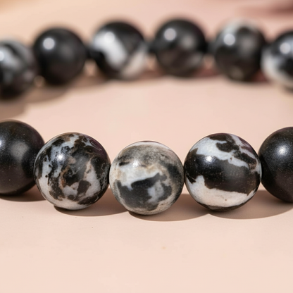 Extreme close-up of Zebra Jasper gemstone beads showing natural black and white patterns on soft blush surface with gentle shadow. — for Carpe Diem Dream
