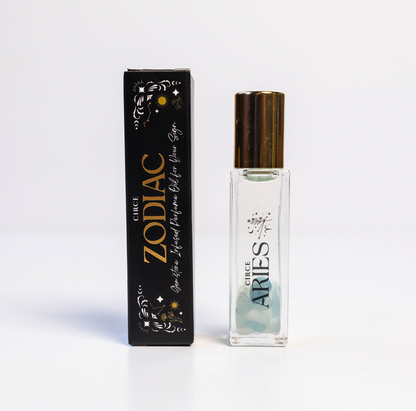 Aries zodiac gemstone perfume oil rollerball with aquamarine crystals displayed beside zodiac packaging on a white background. — for Carpe Diem Dream