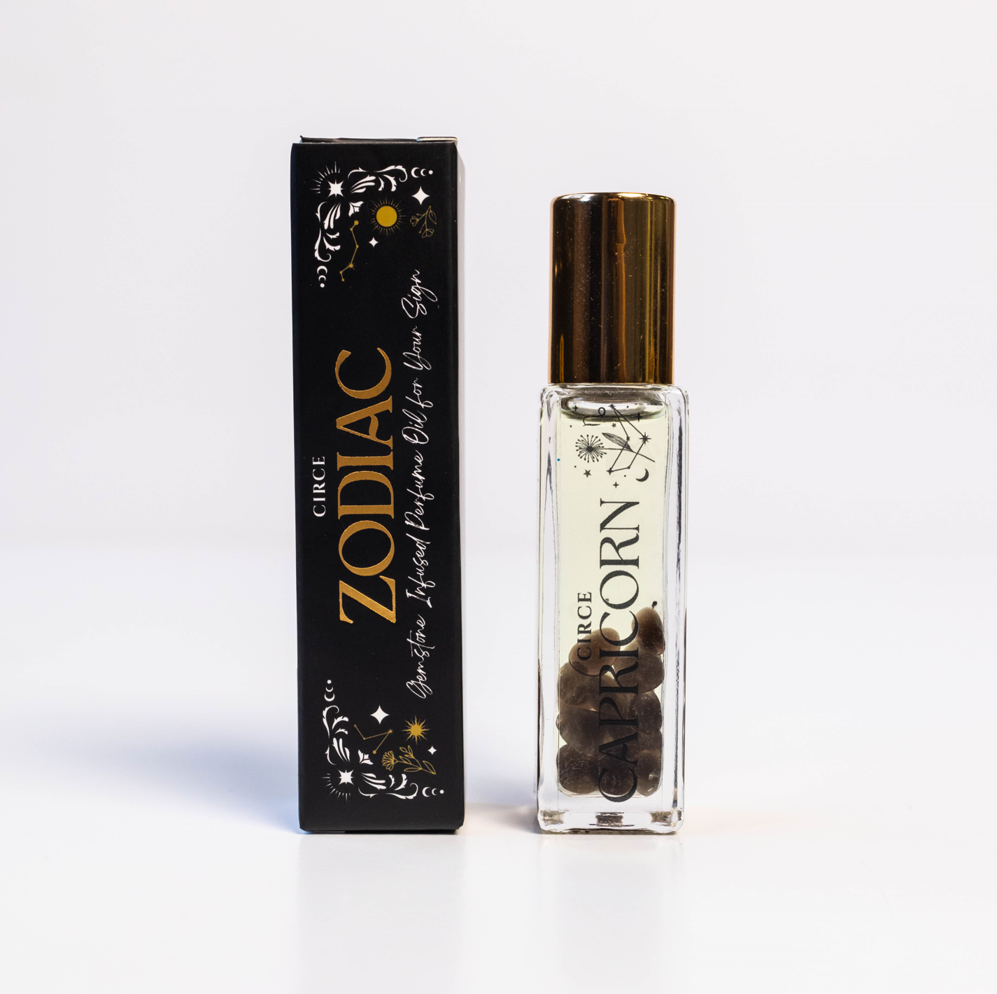 Capricorn zodiac gemstone perfume oil rollerball with smoky quartz crystals displayed beside zodiac packaging on a white background. — for Carpe Diem Dream